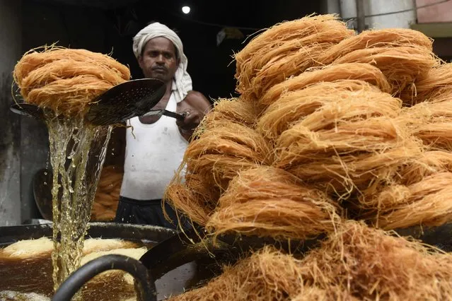 A worker cooks vermicelli at a stall ahead of the “Karva Chauth” festival, in which married women fast one whole day and offer prayers to the moon for the welfare, prosperity, and longevity of their husbands, in Amritsar on October 7, 2022. (Photo by Narinder Nanu/AFP Photo)