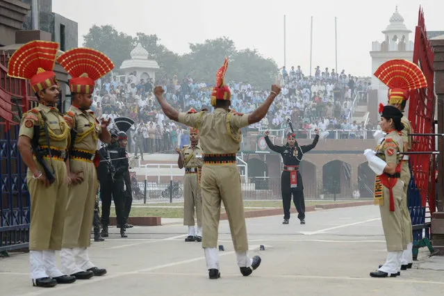 This photo taken on October 30, 2017 shows Indian Border Security Force personnel (brown) and Pakistani rangers (black) taking part in the daily beating of the retreat ceremony at the India-Pakistan Wagah Border, some 35km west of Amritsar. (Photo by Narinder Nanu/AFP Photo)