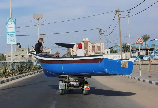 Palestinians sit in a fishing boat loaded into a horse cart as they pass on a street in the northern Gaza Strip on October 19, 2022. (Photo by Suhaib Salem/Reuters)