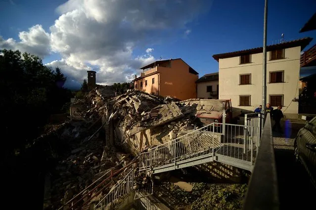 Residents walk past damaged buildings after a strong heartquake hit Amatrice on August 24, 2016. Central Italy was struck by a powerful, 6.2-magnitude earthquake in the early hours, which has killed at least three people and devastated dozens of mountain villages. Numerous buildings had collapsed in communities close to the epicenter of the quake near the town of Norcia in the region of Umbria, witnesses told Italian media, with an increase in the death toll highly likely. (Photo by Filippo Monteforte/AFP Photo)