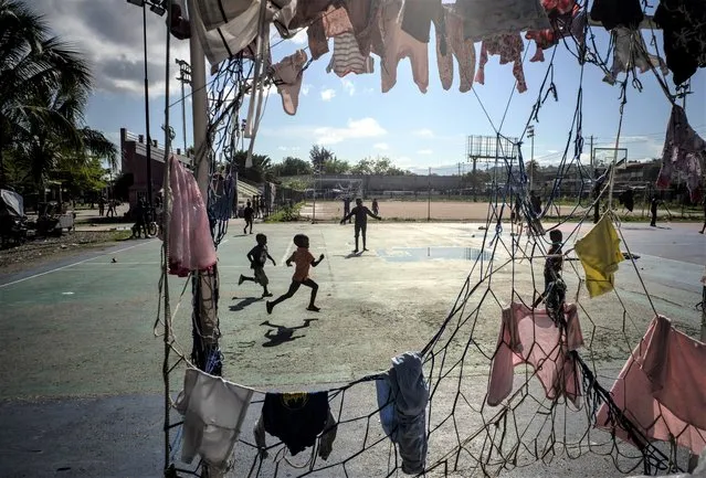 Children run past a goal post used to hang clothes at the Hugo Chavez public square transformed into a refuge for families forced to leave their homes due to clashes between armed gangs in Port-au-Prince, Haiti, Thursday, October 20, 2022. (Photo by Ramon Espinosa/AP Photo)