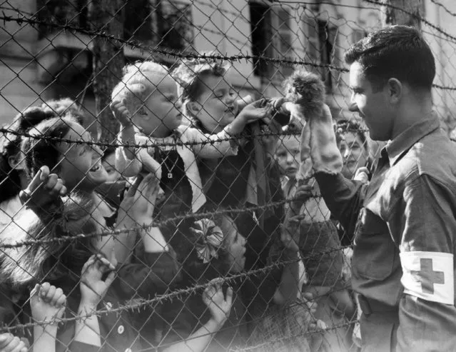 Pfc. Elbon Nicholas of Cadillac, Mich., uses a toy monkey to entertain a few of the more youthful of the 1,500 internees of the German internment camp at Vittel, in the Vosges mountains of France on September 21, 1944. The internees, citizens of the United States, England, and other Allied Nations, were released after the arrival of French troops from Gen. Patton's Third Army on September 13. (Photo by AP Photo)