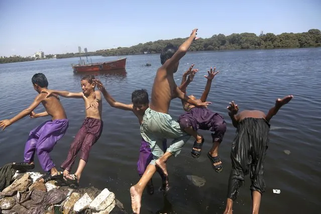Kids jump into water to cool themselves off as the temperature soars in Karachi, Pakistan, Wednesday, June 24, 2020. Many cities in Pakistan are facing heat wave conditions with temperatures reaching 46 C (114 F) in some places. (Photo by Fareed Khan/AP Photo)