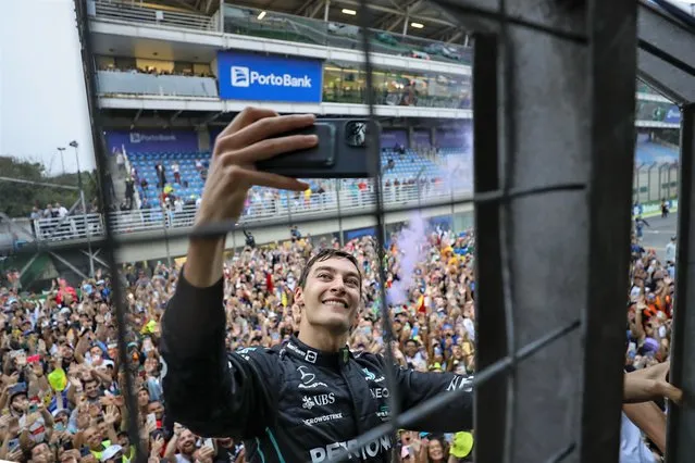 Mercedes driver George Russell, of Britain, takes a selfie with the crowd in the background after winning the Brazilian Formula One Grand Prix at the Interlagos race track in Sao Paulo, Brazil, Sunday, November 13, 2022. (Photo by Marcelo Chello/AP Photo)