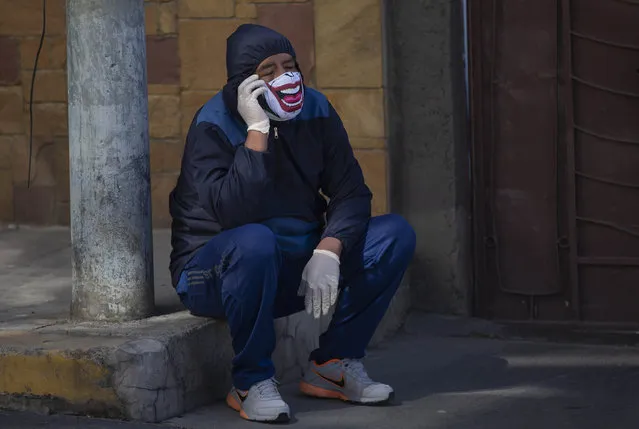 A man wearing a mask speaks on his mobile phone as waits to be tested during a house-to-house new coronavirus testing drive, in the Villa San Luis neighborhood of La Paz, Bolivia, Sunday, July 19, 2020. (Photo by Juan Karita/AP Photo)