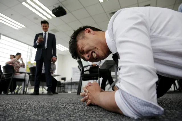 A trainer (L) checks the time of a dealership sales staff holding on to a plank posture as a part of program during a sales camp at BMW Group Training Center in Beijing, China, September 9, 2015. At BMW, where deliveries to dealers in China have grown just 1 percent so far this year, this means putting recruits through sales 'boot camp' and turning experienced staff into spreadsheet wonks. The world's top luxury car maker this month opened its largest Asia training centre in Xi'an in Shaanxi province. (Photo by Kim Kyung-Hoon/Reuters)