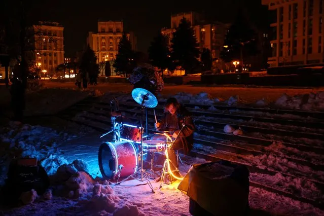 A street musician plays during snowfall as power outages continue in Kyiv, Ukraine on December 3, 2022. (Photo by Shannon Stapleton/Reuters)