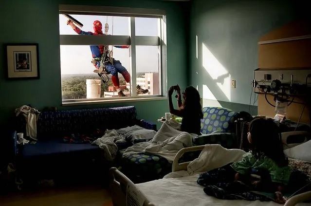 Sao Doan, 5, right, watches as  her mom, Tiffany Ringer, both of Kenneth City, snaps a photo of Merrill Hunt dressed as  Spiderman as he washes her window at All Children's Hospital in St. Petersburg, January 10, 2013. (Photo by Cherie Diez/The Tampa Bay Times)