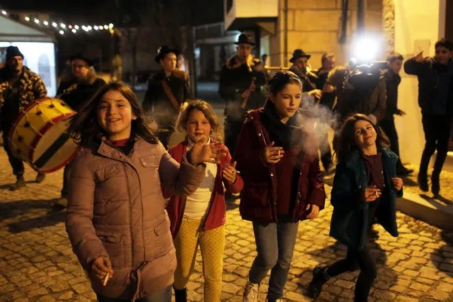 Children smoke while walking with a music band in the village of Vale de Salgueiro, northern Portugal, during the local Kings' Feast Friday night, January 5, 2018. The village's Epiphany celebrations, called Kings' Feast, feature a tradition that each year causes an outcry among outsiders: parents encourage their children, some as young as 5, to smoke cigarettes. The local tradition dictates that children as young as five are permitted to smoke on the special occasion, despite the legal buying age for tobacco being 18 in Portugal. Every year the event, called the King's Feast, draws outrage and strong criticism from outsiders. But despite the annual backlash, parents have continued to honour the allegedly centuries-old tradition by purchasing packets of cigarettes for their kids. The practice is technically legal in the country as nothing in the law prohibits parents giving children cigarettes and authorities do not intervene to stop them. (Photo by Armando Franca/AP Photo)