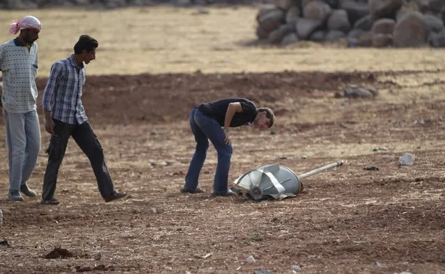 Men inspect the remains of a rocket that activists say was fired by the Russian air force at Maasran town, in the southern countryside of Idlib, Syria October 7, 2015. (Photo by Khalil Ashawi/Reuters)