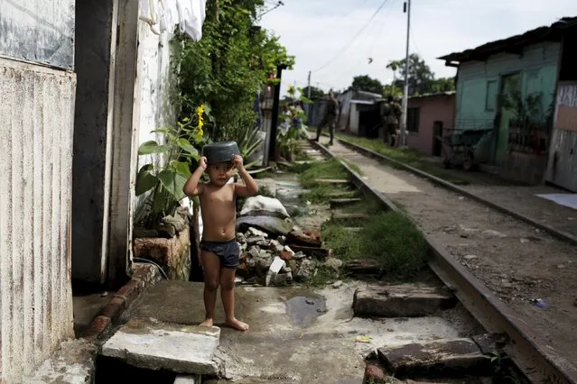 A child observes army soldiers as they participate in a patrol operation after residents flee the Amaya Community, due to threats from suspected gang members, in San Salvador, October 13, 2015. (Photo by Jose Cabezas/Reuters)