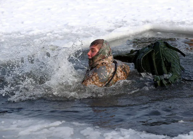 A soldier of NATO's Enhanced Forward Presence battle group swims in the icy water during the winter survival exercise in Adazi, Latvia February 8, 2018. (Photo by Ints Kalnins/Reuters)