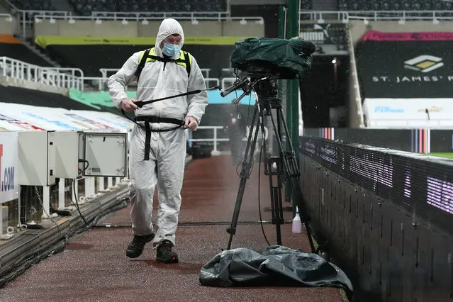 A member of staff wearing full PPE disinfects a TV camera amidst the COVID-19 pandemic during the Premier League match between Newcastle United and Burnley at St. James Park on October 03, 2020 in Newcastle upon Tyne, England. Sporting stadiums around the UK remain under strict restrictions due to the Coronavirus Pandemic as Government social distancing laws prohibit fans inside venues resulting in games being played behind closed doors. (Photo by Scott Heppell – Pool/Getty Images)