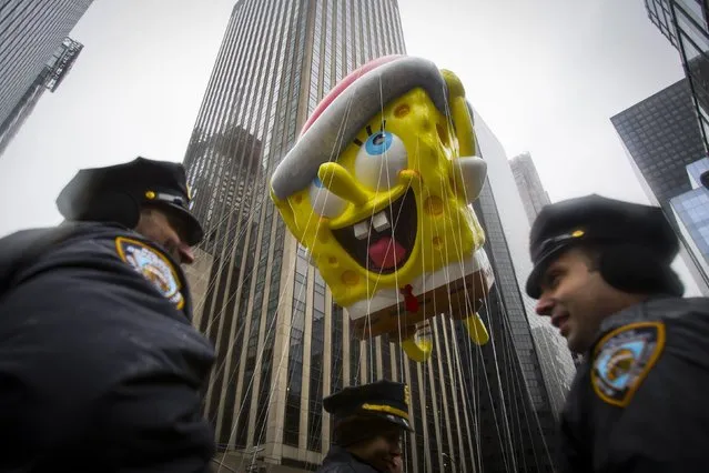 The Spongebob Squarepants balloon floats by New York Police Officers during the 88th Annual Macy's Thanksgiving Day Parade in New York November 27, 2014. (Photo by Andrew Kelly/Reuters)