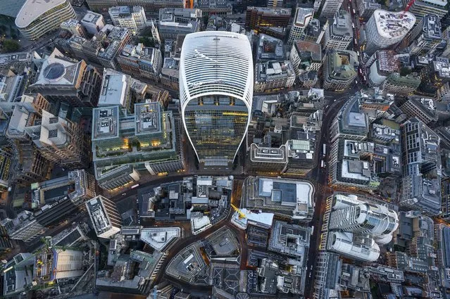 High-flying photographer Jeffrey Milstein, renowned for his aerial photos of US cities, snaps landmarks through the open door of a helicopter. This month he hired a chopper in London and amazingly he had just an hour to cover all the buildings he wanted to capture including Buckingham Palace, the London Eye, the glass roof of the British Museum and the Gherkin and Walkie Talkie towers in the City. Here: The Walkie Talkie, built two years ago, is one of dozens of new towers in the ancient City. (Photo by Jeffrey Milstein/Rex Features/Shutterstock)