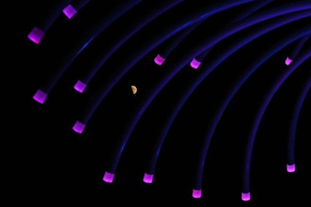 A half moon rises beyond a sculpture in a park in Leawood, Kan., Friday, August 1, 2025. (Photo by Charlie Riedel/AP Photo)