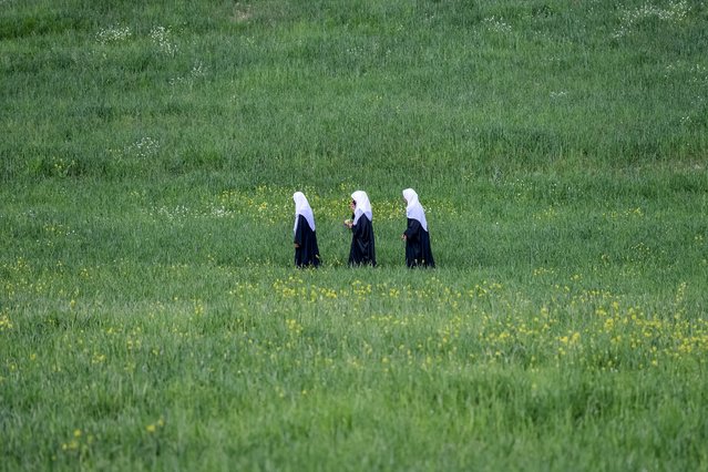 Afghan school girls walk through a field in Fayzabad district of Badakhshan Province on April 22, 2025. (Photo by Omer Abrar/AFP Photo)