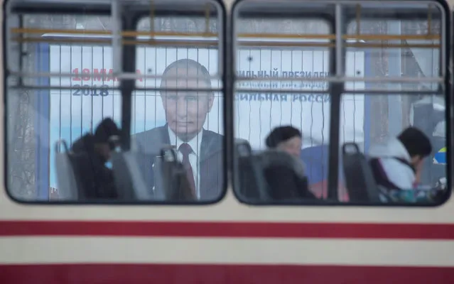 People ride a tram past a board, which advertises the campaign of Russian President Vladimir Putin ahead of the upcoming presidential election, on a street in St. Petersburg, Russia February 19, 2018. (Photo by Anton Vaganov/Reuters)