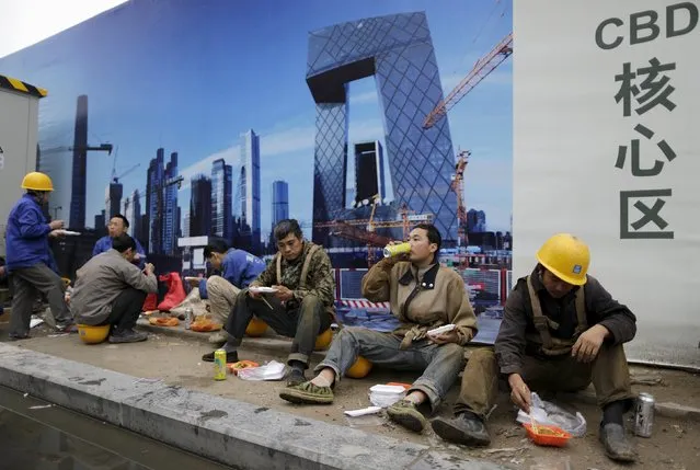 Construction workers have lunch as they sit in front of a poster bearing a picture of the Central Business District (CBD) area, outside a construction site in Beijing, China, October 26, 2015. China's ruling Communist Party opened a key meeting on Monday that will focus on financial reforms and how to maintain growth of around seven percent and more broadly map out economic and social targets for the next five years. (Photo by Jason Lee/Reuters)