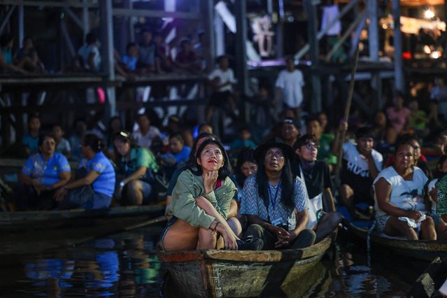 Spectators sit on boats watching a film projected on a screen during the Muyuna Floating Film Festival, at the Belen district in Iquitos, northern Peru on May 24, 2024. The Muyuna festival emerges as the first floating jungle film competition, a space where the world's jungles are cited with the aim of promoting their protection and the cultural expression of the people who inhabit them through the creation and dissemination of audiovisual stories. (Photo by Hugo Curotto/AFP Photo)