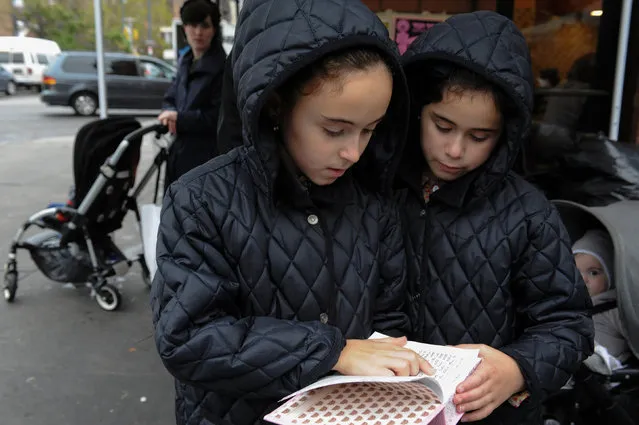 Two girls read the Torah while people participate in the Jewish religious holiday of Kaporos in the Brooklyn borough of New York City, October 9, 2016. (Photo by Stephanie Keith/Reuters)