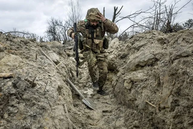 Ukrainian medic “Doc” with the 28th Brigade runs through a partially dug trench along the frontline on March 05, 2023 outside of Bakhmut, Ukraine. The Ukrainian Army medic, an Odessa dentist in civilian life, said was a guitarist in band Uragan Metal for 13 years before he joined the Army following the Russian invasion. Russian forces have been attacking Ukrainian troops as part of an offensive to encircle Bakhmut in Ukraine's eastern Donbas region. (Photo by John Moore/Getty Images)