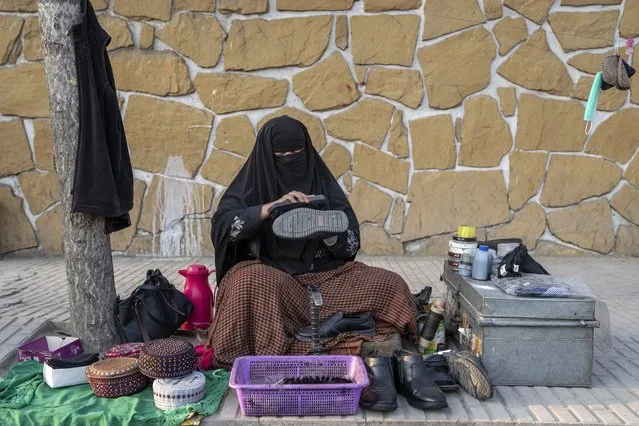 An Afghan woman cleans customers's shoes in a street in Kabul, Afghanistan, Sunday, March 5, 2023. After the Taliban came to power in Afghanistan, women have been deprived of many of their basic rights. (Photo by Ebrahim Noroozi/AP Photo)