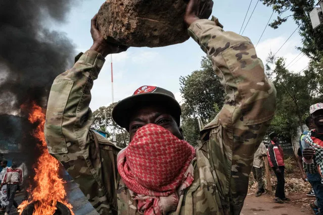 A protester gestures with a rock during a mass rally called by the opposition leader Raila Odinga who claims the last Kenyan presidential election was stolen from him and blames the government for the hike of living costs in Kibera, Nairobi on March 20, 2023. Kenya's opposition leader Raila Odinga called on his supporters to participate in countrywide protests on March 20, 2023 to demand that President William Ruto lowers the cost of living while questioning last year’s presidential elections results. Kenyans face economic hardship following the government’s recent tax measures and increased food and fuel prices. (Photo by Yasuyoshi Chiba/AFP Photo)