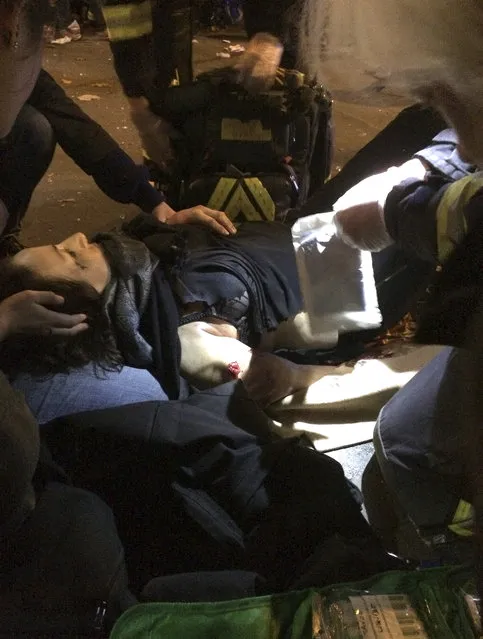 A Victim of a shooting attack is treated on the pavement outside La Belle Equipe restaurant in Paris Friday, November 13, 2015. (Photo by Anne Sophie Chaisemartin via AP Photo)