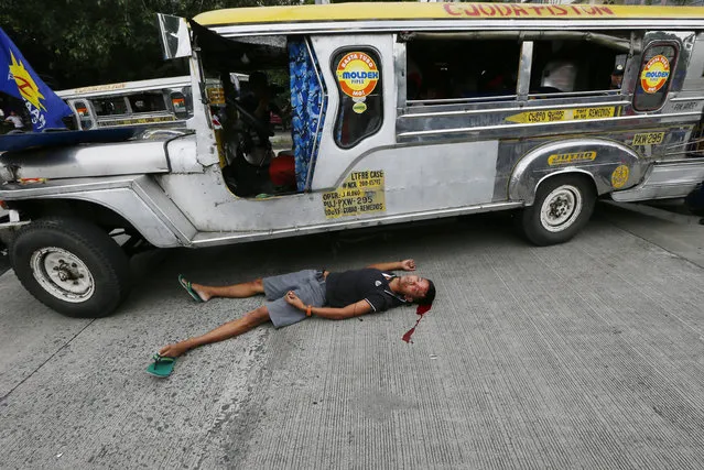 A bloodied protester lies next to a passenger vehicle after he was injured in a violent dispersal outside the U.S. Embassy in Manila, Philippines Wednesday, October 19, 2016. A Philippine police van rammed into protesters, leaving several bloodied, as an anti-U.S. rally turned violent Wednesday at the American embassy in Manila. (Photo by Bullit Marquez/AP Photo)