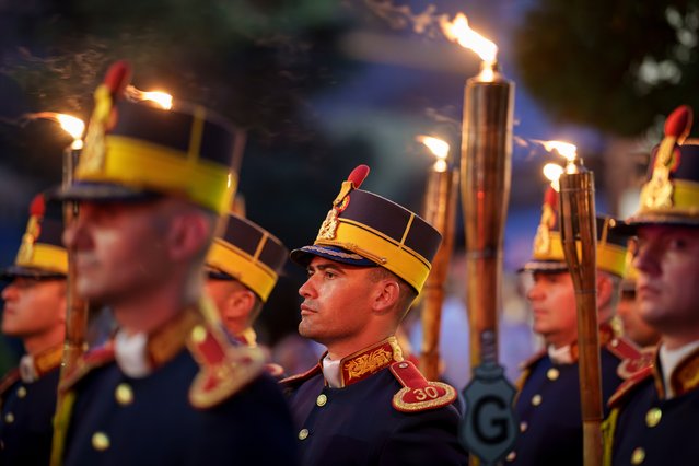 Members of an honor guard hold torches before marching in memory of the country's war heroes in Bucharest, Romania, Thursday, June 13, 2024. Romanians celebrate the memory of war heroes on Ascension Day, forty days after Orthodox Easter. (Photo by Vadim Ghirda/AP Photo)