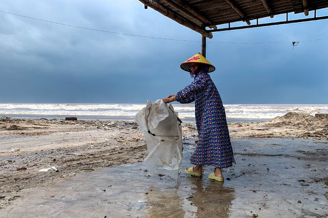 A woman wearing a raincoat collects a plastic bag near a beach as Typhoon Bualoi nears, in Nghe An province, Vietnam, on September 28, 2025. (Photo by Thinh Nguyen/Reuters)