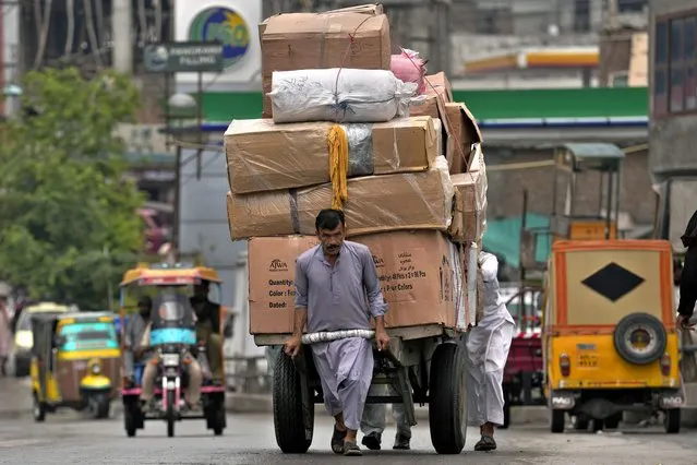 Laborer pull a heavy loaded hand-cart on a road on the International Labor Day, in Rawalpindi, Pakistan, Monday, May 1, 2023. In Pakistan, authorities have banned rallies in some cities due to a tense security situation or political atmosphere. Labor organizations and trade unions held indoor events on May Day to demand implementation of labor laws and increase in their wages. (Photo by Anjum Naveed/AP Photo)