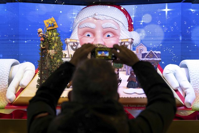 A person takes a picture of the window displays outside Macy's flagship store, Wednesday, December 10, 2025, in New York. (Photo by Yuki Iwamura/AP Photo)