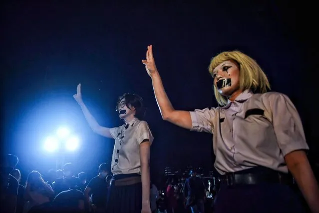 Students flash the three-fingered Hunger Games salute at an anti-government rally at Mahidol University in Nakhon Pathom on August 18, 2020. The country has seen near-daily protests in recent weeks by university students demanding the resignation of Prime Minister Prayut Chan-O-Cha and a frank discussion of the role of the unassailable monarchy. (Photo by Lillian Suwanrumpha/AFP Photo)