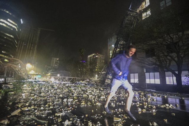 Joe Lindquist, 32, of St. Petersburg, walks over bricks near a fallen crane along 1st Avenue South near the Tampa Bay Times offices in St. Petersburg, Florida, Thursday, October 10, 2024, as Hurricane Milton's strong winds tore through the area. (Photo by Chris Urso/Tampa Bay Times via AP Photo)