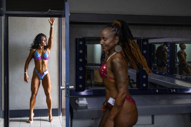 An athlete stretches as she warms up ahead of her show as an other athlete gets ready backstage before competing in the 2024 International Fitness and Bodybuilding Federation (IFBB) Xtyle Fitness and Entertainment (XFE) Classic Fitness and Bodybuilding Show in Kempton Park Civic Centre in Ekurhuleni, on December 7, 2024. This event is part of the IFBB Fitness and Bodybuilding Events in South Africa, an official qualifying event for the prestigious Arnold Classic Africa and also forms part of the IFBB Platinum League. (Photo by Roberta Ciuccio/AFP Photo)