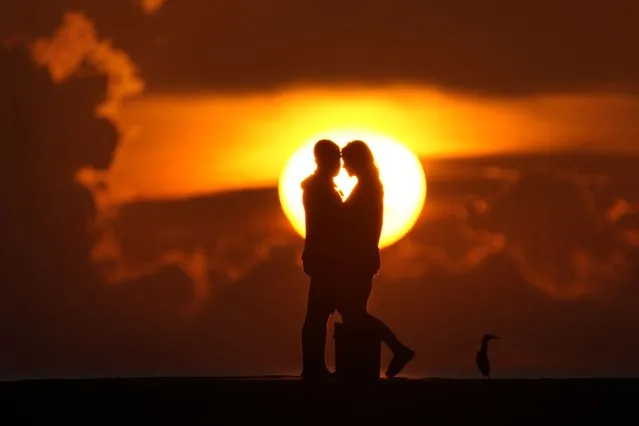 A couple watches the sun rise over the Atlantic Ocean, Wednesday, June 28, 2023, in Bal Harbour, Fla. A heat dome is spreading eastward from Texas and by the weekend is expected to be centered over the mid-South, said meteorologist Bryan Jackson with the National Weather Service in College Park, Maryland. (Photo by Wilfredo Lee/AP Photo)