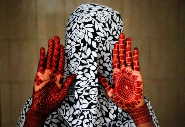 A Muslim woman shows her hands with henna tattoos a day ahead of Eid al-Adha, in Adjame, Abidjan, Ivory Coast on June 27, 2023. (Photo by Luc Gnago/Reuters)