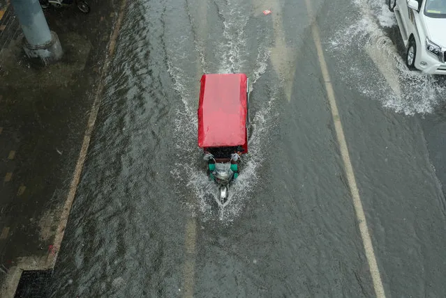 A tricycle makes its way along a flooded street in Beijing on July 20, 2016. Some areas and streets in Beijing have started to flood over due to heavy rain. (Photo by AFP Photo/Stringer)