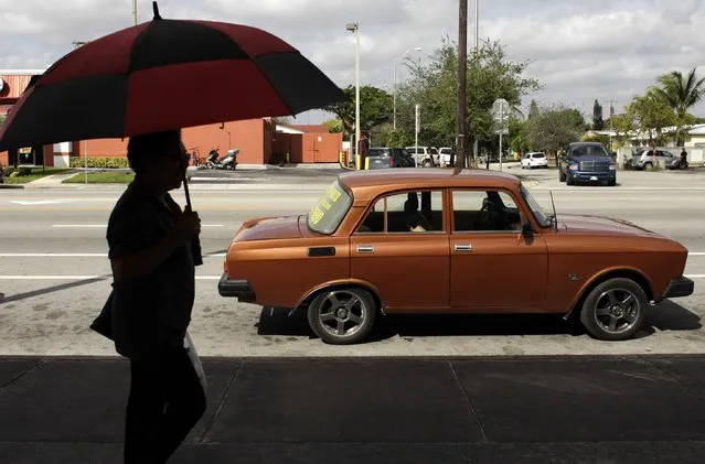 A woman walks past a Moskvich car in front of Fabian Zakharov's Zakharov Auto Parts shop in Hialeah, Florida, February 4, 2015. (Photo by Javier Galeano/Reuters)