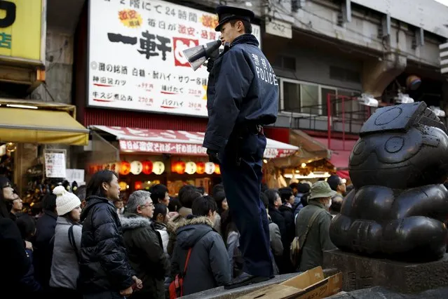 A police officer directs the crowd as people shop for food and goods at Ameyoko market ahead of the New Year holidays in Tokyo, Japan, December 30, 2015. (Photo by Thomas Peter/Reuters)