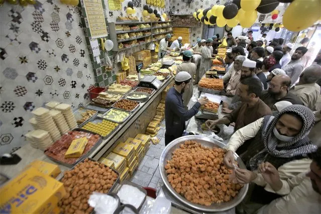 People buy traditional sweets in preparation for the upcoming Eid al-Fitr celebrations, at a shop, in Peshawar, Pakistan, Thursday, April 20, 2023. Eid al-Fitr marks the end of the Islamic holy month of Ramadan. (Photo by Muhammad Sajjad/AP Photo)