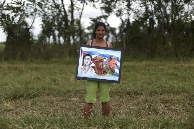 Yoani Gomes, 43, holds images of Fidel Castro as she awaits the arrival of the caravan carrying the late Cuban President's ashes in El Maja, Cuba, December 1, 2016. (Photo by Alexandre Meneghini/Reuters)