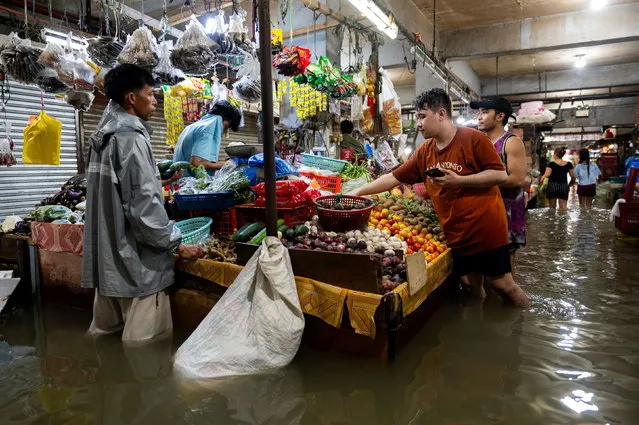 People shop at a market flooded by monsoon rains and the recent typhoon Doksuri, in Balagtas, Bulacan province, Philippines on July 29, 2023. (Photo by Lisa Marie David/Reuters)