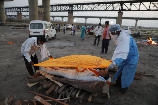 Family members place a cloth on the body of Rajendra Prasad Mishra, 62, who died due to COVID-19 before cremation by the River Ganges in Prayagraj, India, Saturday, May 8, 2021. (Photo by Rajesh Kumar Singh/AP Photo)