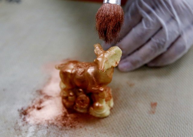 A chef paints a goat-shaped chocolate with edible gold powder, as he prepares to make a cake celebrating the upcoming Chinese Lunar New Year, during a photo opportunity at a kitchen of Kerry Hotel in Beijing, February 12, 2015. (Photo by Kim Kyung-Hoon/Reuters)