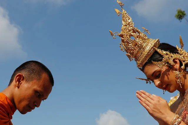 A woman dressed in traditional Thai costume offers alms to a Buddhist monk during the Songkran celebrations, to commemorate the Thai New Year in Bangkok, Thailand April 13, 2018. (Photo by Jorge Silva/Reuters)