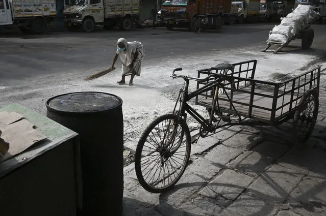 A woman collects slaked Lime from the ground at a wholesale market during a 15-day lockdown announced by West Bengal's government to curb the spread of the Covid-19 coronavirus, in Kolkata on May 19, 2021. (Photo by Dibyangshu Sarkar/AFP Photo)