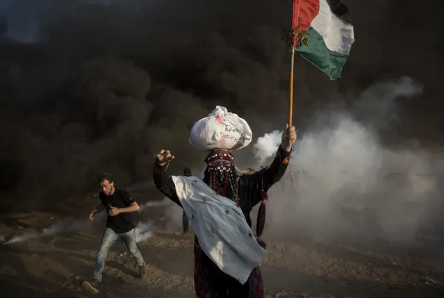 Palestinian protesters run for cover from teargas fired by Israeli troops during a protest at the Gaza Strip's border with Israel, Friday, October 12, 2018. (Photo by Khalil Hamra/AP Photo)